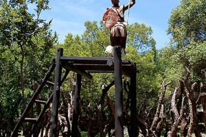 Giovane guerriero Zulu fa da sentinella poco distante dall'entrata del villaggio su una pedana sopraelevata a circa tre metri di altezza dal suolo; Aha Lesedi Village; Sud Africa 2012