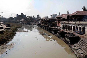 I funerali Hindu, circa 4.000 anni fa, prevedevano la sepoltura nella terra, nelle grotte o i corpi venivano affidati allo scorrere dei fiumi. Con il trascorrere degli anni i defunti hanno iniziato ad essere sottoposti al processo di cremazione (ad esclusione dei neonati, dei  bambini, dei santi e dei morti a causa di pestilenza), in quanto solo attraverso questo rituale fondamentale si poteva garantire un passaggio veloce e puro dell'anima ad una nuova dimensione: tale passaggio infatti viene vanificato sino a quando esiste il corpo mortale. Il complesso dei rituali funebri Hinduisti viene denominato "Antyeshti", cioè l'ultimo sacrificio. Quando una persona è in punto di morte viene posto il suo viso in direzione dell'Est e viene accesa una lanterna accanto al suo corpo. Viene contattato un sacerdote hinduista che, insieme ai parenti, recita versi sacri (simili ai Mantra) tentando di rianimare il moribondo. A morte avvenuta vengono versate sulle labbra del trapassato gocce di latte o di acqua di un fiume sacro, mentre sulla fronte si effettuano dei segni particolari con la pasta di sandalo. I parenti raccolti intorno al defunto evitano di toccare il corpo che, all'atto della morte avvenuta, è considerato impuro. I funerali dovrebbero avvenire il prima possibile, in genere dal crepuscolo successivo al decesso o dall'alba. Secondo la tradizione, il corpo viene lavato dai membri della famiglia e dagli amici più stretti, orientando il capo del defunto verso sud e viene posta una lampada ad olio illuminata, oltre ad una immagine della Divinità preferita quando era ancora in vita, al di sopra della sua testa. Si passa, seguendo il tradizionale rituale, al santo bagno ("Abhisegam" in lingua Hindu) che prevede il lavaggio del corpo in una miscela di latte, yogurt, "ghee" (burro chiarificato) e miele, oppure in acqua purificata, mentre si recitano i mantra. Una volta che il lavaggio rituale si è concluso, le dita grandi vengono legate insieme, le mani vengono posizionate palmo contro palmo nella postura di preghiera ed infine il corpo è avvolto in un telo bianco. Se una donna sposata viene meno prima rispetto al marito, il suo corpo sarà vestito di rosso. Segue una breve veglia, durante la quale il corpo viene visualizzato in un semplice scrigno, mentre il "vibuti" ( la cenere) od il "chandanam" (il legno di sandalo) viene applicato sulla fronte degli uomini e la curcuma sulla fronte delle donne. Una ghirlanda di fiori va disposta intorno al collo ed il basilico santo viene collocato nello scrigno, mentre i parenti e gli amici, posizionati tutt'intorno allo scrigno, cantano e recitano inni e mantra. Al termine della veglia, prima che il corpo venga rimosso per essere trasportato nel luogo di cremazione, molti dei presenti offrono al defunto i "pinda" (delle palle di riso). Il corpo da cremare viene trasportato su una barella a piedi (se il sito non risultassse troppo distante), oppure in macchina: in tal caso il maggiore maschio più anziano insieme ad un altro anziano devono accompagnare la salma. Per consuetudine solo gli uomini possono partecipare allla cremazione. Storicamente le cremazioni Hindu vengono svolte sulle rive di un fiume sacro (dal Gange al Bagmati, ad esempio): i parenti presenti al rito costruiscono una pira (acquistando la legna necessaria dai commercianti di legname che ha un costo molto elevato rispetto alle condizioni economiche della maggior parte degli Hindu, come degli stessi nepalesi), più la pira risulterà alta, maggiore sarà l'importanza sociale del defunto e più elevata la spesa da affrontare per i parenti. Il "Karta" (il rito funebre in senso stretto) dovrà essere eseguito dal figlio maggiore o dal parente maschio più anziano: egli dovrà girare attorno alla pira per 3 o 7 volte, presentandole il fianco destro (quindi in senso orario) e recitando una formula propriziatoria ("Pradakshina"), mentre spruzzerà acqua santa sulla pira. Posizionerà sette gocce di burro nella bocca, negli occhi e nelle narici del defunto ed infine accenderà il fuoco nella pira partendo dal cuore. Sino a quando il corpo non risulterà completamente bruciato, si continueranno a cantare mantra e salmi. Al termine tutti i presenti verseranno acqua sui resti e le ceneri verranno raccolte il giorno successivo, dividendo quelle relative al corpo (più chiare) rispetto a quelle della legna bruciata. Una volta separate e raccolte le ceneri, esse verranno immerse nelle acque di un fiume sacro, sempre a cura del figlio maschio maggiore. Terminata la cremazione si darà inizio al periodo di lutto che durerà 13 giorni. Pashupatinath, Kathmandu, Nepal 2018.