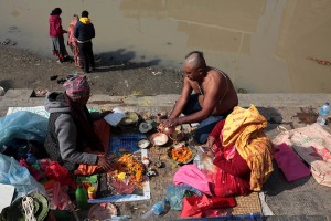 Sui marciapiedi che cingono le sponde del fiume sacro Bagmati si trovano molti santoni che svolgono i loro riti dietro richiesta dei pellegrini: la presunta capacità di attingere ad informazioni da fonti soprannaturali, in genere ritenute inaccessibili per i comuni mortali, mediante rituali religiosi e spirituali, rendono i servigi di questi individui molto ricercati ed apprezzati. Possono essere eseguite interpretazioni di segni, eventi, simboli, presagi o sogni, pratiche di predizione del futuro, cerimonie e pratiche magiche o presunte tali per allontanare la mala sorte. Pashupatinath, Kathmandu, Nepal 2018.