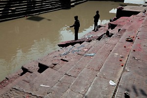 Nei Ghat orientali posti lungo il fiume sacro Bagmati e sulle scalinate adiacenti, incontro questi bambini con una lenza in mano: credo che, in prima battuta, stiano provando a pescare nelle torbide acque, invece scopro che una calamita è assicurata all'estremità del cordino per raccogliere le monete che i pellegrini gettano nel fiume sacro come segno di buon auspicio, Pashupatinath, Kathmandu, Nepal 2018.