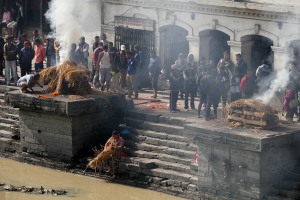 I funerali Hindu, circa 4.000 anni fa, prevedevano la sepoltura nella terra, nelle grotte o i corpi venivano affidati allo scorrere dei fiumi. Con il trascorrere degli anni i defunti hanno iniziato ad essere sottoposti al processo di cremazione (ad esclusione dei neonati, dei  bambini, dei santi e dei morti a causa di pestilenza), in quanto solo attraverso questo rituale fondamentale si poteva garantire un passaggio veloce e puro dell'anima ad una nuova dimensione: tale passaggio infatti viene vanificato sino a quando esiste il corpo mortale. Il complesso dei rituali funebri Hinduisti viene denominato "Antyeshti", cioè l'ultimo sacrificio. Quando una persona è in punto di morte viene posto il suo viso in direzione dell'Est e viene accesa una lanterna accanto al suo corpo. Viene contattato un sacerdote hinduista che, insieme ai parenti, recita versi sacri (simili ai Mantra) tentando di rianimare il moribondo. A morte avvenuta vengono versate sulle labbra del trapassato gocce di latte o di acqua di un fiume sacro, mentre sulla fronte si effettuano dei segni particolari con la pasta di sandalo. I parenti raccolti intorno al defunto evitano di toccare il corpo che, all'atto della morte avvenuta, è considerato impuro. I funerali dovrebbero avvenire il prima possibile, in genere dal crepuscolo successivo al decesso o dall'alba. Secondo la tradizione, il corpo viene lavato dai membri della famiglia e dagli amici più stretti, orientando il capo del defunto verso sud e viene posta una lampada ad olio illuminata, oltre ad una immagine della Divinità preferita quando era ancora in vita, al di sopra della sua testa. Si passa, seguendo il tradizionale rituale, al santo bagno ("Abhisegam" in lingua Hindu) che prevede il lavaggio del corpo in una miscela di latte, yogurt, "ghee" (burro chiarificato) e miele, oppure in acqua purificata, mentre si recitano i mantra. Una volta che il lavaggio rituale si è concluso, le dita grandi vengono legate insieme, le mani vengono posizionate palmo contro palmo nella postura di preghiera ed infine il corpo è avvolto in un telo bianco. Se una donna sposata viene meno prima rispetto al marito, il suo corpo sarà vestito di rosso. Segue una breve veglia, durante la quale il corpo viene visualizzato in un semplice scrigno, mentre il "vibuti" ( la cenere) od il "chandanam" (il legno di sandalo) viene applicato sulla fronte degli uomini e la curcuma sulla fronte delle donne. Una ghirlanda di fiori va disposta intorno al collo ed il basilico santo viene collocato nello scrigno, mentre i parenti e gli amici, posizionati tutt'intorno allo scrigno, cantano e recitano inni e mantra. Al termine della veglia, prima che il corpo venga rimosso per essere trasportato nel luogo di cremazione, molti dei presenti offrono al defunto i "pinda" (delle palle di riso). Il corpo da cremare viene trasportato su una barella a piedi (se il sito non risultassse troppo distante), oppure in macchina: in tal caso il maggiore maschio più anziano insieme ad un altro anziano devono accompagnare la salma. Per consuetudine solo gli uomini possono partecipare allla cremazione. Storicamente le cremazioni Hindu vengono svolte sulle rive di un fiume sacro (dal Gange al Bagmati, ad esempio): i parenti presenti al rito costruiscono una pira (acquistando la legna necessaria dai commercianti di legname che ha un costo molto elevato rispetto alle condizioni economiche della maggior parte degli Hindu, come degli stessi nepalesi), più la pira risulterà alta, maggiore sarà l'importanza sociale del defunto e più elevata la spesa da affrontare per i parenti. Il "Karta" (il rito funebre in senso stretto) dovrà essere eseguito dal figlio maggiore o dal parente maschio più anziano: egli dovrà girare attorno alla pira per 3 o 7 volte, presentandole il fianco destro (quindi in senso orario) e recitando una formula propriziatoria ("Pradakshina"), mentre spruzzerà acqua santa sulla pira. Posizionerà sette gocce di burro nella bocca, negli occhi e nelle narici del defunto ed infine accenderà il fuoco nella pira partendo dal cuore. Sino a quando il corpo non risulterà completamente bruciato, si continueranno a cantare mantra e salmi. Al termine tutti i presenti verseranno acqua sui resti e le ceneri verranno raccolte il giorno successivo, dividendo quelle relative al corpo (più chiare) rispetto a quelle della legna bruciata. Una volta separate e raccolte le ceneri, esse verranno immerse nelle acque di un fiume sacro, sempre a cura del figlio maschio maggiore. Terminata la cremazione si darà inizio al periodo di lutto che durerà 13 giorni. Pashupatinath, Kathmandu, Nepal 2018.