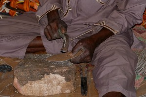 Ciabattino batte dei chiodini su una suola di pelle, con cui realizzerà un paio di sandali, Mercato dell'Artigianato all'interno del Museo Nazionale Etnografico di Niamey, Niger 2020