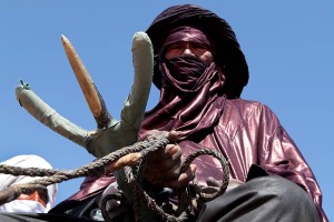 Cavaliere Tuareg serra tra le sue mani le redini del dromedario che sta montando, Festival dell'Air, Iferouane, Deserto del Ténéré, Regione dell'Air, Niger 2020