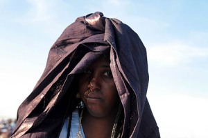 Donna Tuareg Kel Ferouane con i vestiti tradizionali di festa: l'Afer (un mantello o panno che copre il corpo dalla vita alle ginocchia in tessuto colorato, stampato o ricamato), l'Aftek (una camicetta), l'lseggelmas (velo che lascia scoperto il viso ed una parte della capigliatura, lasciando intravedere le trecce), Festival dell'Air, Iferouane, Deserto del Ténéré, Regione dell'Air, Niger 2020