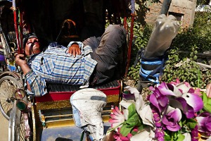 Un "risciò man" dorme sul sedile del suo mezzo dopo una giornata particolarmente faticosa: la sua è una vita di sacrifici e di ristrettezza, deve pagare un affitto giornaliero pesante ed a lui restano solo le briciole rispetto al ricavato quotidiano. Kathmandu, Nepal 2018.