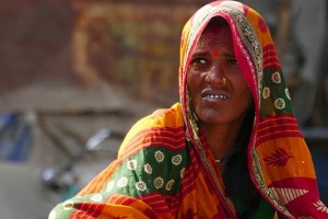 Una donna "Dalit", cioè appartenente agli Intoccabili: in Nepal esistono tra i 3,6 ed i 5 milioni di persone con questo status sociale così discriminante, il che significa che essi comprendono quasi un quinto della popolazione totale. Vi è la credenza diffusa che le persone di casta superiore abbiano avuto origine dalla bocca, dalle braccia o dalle cosce di Dio, mentre i Dalit dai piedi. Il sistema delle caste in Nepal è stato ufficialmente abolito nel lontano 1962, ma tale gerarchia sociale risulta ancora applicata nella vita quotidiana del Paese, d'altrocanto la religione Hinduista impedisce di fatto l'abrogazione delle caste. Le principali caste vengono denominate "Varna" il cui significato è "colori" perchè ogni casta ha il suo colore di appartenenza. Il termine casta in sanscrito si traduce in "nascita". L'atto di nascere pertanto permette di entrare a far parte di una casta. La casta non si sceglie, viene determinata dalla famiglia di appartenenza, dal cognome che si possiede, dal mestiere e dal colore della pelle. In tale contesto i Dalit sono gli unici a lavorare il cuoio (secondo la religione Hinduista la pelle degli animali può essere trattata esclusivamente da individui considerati impuri), cremano i defunti, seppelliscono gli animali morti, ripuliscono le fogne e le latrine. Questi mestieri così degradanti vengono ereditati da padre in figlio e quindi anche le generazioni future restano impure e non possono ambire ad elevare le proprie condizioni di vita. Questa donna, seduta sul ciglio della strada, chiede l'elemosina nella periferia di Patan, Nepal 2018.