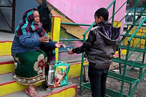 Un bambino nepalese appartenente all'etnia Chhetri ed alla casta Kshatriya acquista un bicchiere di thè masala bollito con latte in polvere, zucchero e spezie da una donna di etnia Tamang, lago di Phewa Tal, Pokhara, Nepal 2018