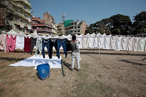 Cheetrapati, un quartiere di Kathmandu dove si concentrano le lavanderie a cielo aperto: uomini e donne, dopo aver lavato a mano i diversi capi di abbigliamento, li stendono sull'erba o su lunghi fili appositamente fissati a pali di legno per farli asciugare. Kathmandu, Nepal 2018