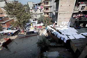 Veduta dall'alto di Cheetrapati, un quartiere di Kathmandu dove si concentrano le lavanderie a cielo aperto: uomini e donne, dopo aver lavato a mano i diversi capi di abbigliamento (anche all'interno di antiche cisterne), li stendono sull'erba o su lunghi fili appositamente fissati a pali di legno per farli asciugare. Kathmandu, Nepal 2018