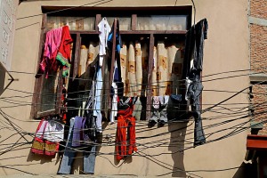 Tra decine di fili elettrici che si accavallano e si intrecciano a poca distanza dalle pareti di questa palazzina, sono stati stesi i vestiti lavati su ogni possibile appiglio del parapetto di questa finestra, nell'antica città Newari di Bhaktapur nella Valle di Kathmandu, Nepal 2018