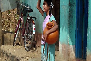 Nel villaggio di Saundatti una ragazza si appresta, uscendo dalla sua abitazione, a raggiungere il vicino lago per raccogliere acqua con l'anfora e lavare i vestiti. Regione del Karnataka, India 2015.