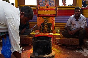 Nel mercato di Saundatti, oltre alle numerose bancarelle che vendono di tutto, vi è questo piccolo Tempio in miniatura dove i pellegrini si soffermano per pregare, per offrire alla Dea Yallamma fiori, polvere di curcuma o di kum kum, frutta, monete e banconote, o per accendere, come nel caso di questo devoto, gli incensi.Regione del Karnataka, India 2015.