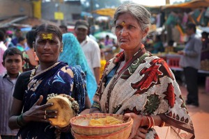 Nel mercato di Saundatti una coppia di enuchi (o "Hijras") chiedono l'elemosina: il più anziano raccoglie le offerte con un cestino di vimini mentre l'altro, più giovane, suona un tamburello con sonagli e campanelli. In passato gli Hijras erano considerati stimati sacerdoti della Dea Yallamma (Dea della fertilità) ed erano accolti con favore nelle corti come guardiani dell'harem o dei templi, maestri delle cerimonie ed a loro potevano essere delegati anche importanti incarichi amministrativi e politici. Ma la loro buona stella tramontò con l'avvento della colonizzazione britannica: nel 1897 viene emanata una legge che dichiara illegali le pratiche omosessuali emarginando, di fatto, una delle più grandi ed antiche comunità transgender del mondo. Oggi gli Hijras vivono segregati nelle baraccopoli dei più grandi centri urbani e nelle megalopoli indiane, sostenendosi con l'accattonaggio e la prostituzione. Regione del Karnataka, India 2015.