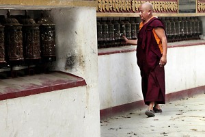 Nello Stupa di Bodhnath un monaco tibetano effettua la circumnavigazione rituale della cupola (in lingua nepali "Kora") sotto gli occhi vigili del Buddha che tutto vede dall'alto della torre dorata centrale, facendo girare con la mano i mulini di preghiera. Questo è uno dei pochi luoghi al mondo dove la cultura buddhista del Tibet è libera di esprimersi senza restrizioni di sorta. Valle di Kathmandu, Nepal 2018