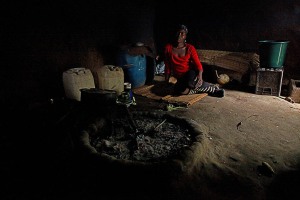 Giovane donna all'interno della propria capanna con al centro il focolare, Swaziland 2012