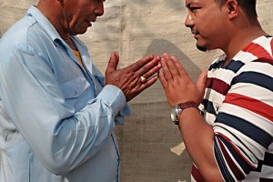 Padre e figlio di etnia Tamang (appartenenti alla casta dei Brahmini) si scambiano il tradizionale saluto "Namastè" (mi inchino alla Divinità che risiede in te), lungolago di Phewa Tal, Pokhara, Nepal 2018