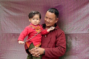 Un giovane papà nepalese appartenente alla casta "Vaisya" (commercianti ed agricoltori), accetta di farsi ritrarre mentre tiene in braccio la sua bellissima bambina, il fondale da me improvvisato è di tessuto di seta broccato che ho acquistato in un vicino mercato, sponde del lago Phewa Tal di Pokhara, Nepal 2018