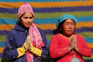 Due donne nepalesi appartenenti alla casta dei "Sudra" dell'etnia Gurung lavorano in uno degli innumerevoli cantieri della ricostruzione dopo il terribile terremoto del 2015: non hanno alcuna tutela e la loro fatica quotidiana supera di gran lunga quella dei loro colleghi maschi, pur percedendo un compenso più basso. Le ho ritratte con lo sfondo di un telo tessuto e dipinto a mano da esperte artigiane, nel gesto a loro familiare del tipico saluto "Namastè" (mi inchino alla Divinità che è in te). Villaggio di Chapagaon, Nepal 2018