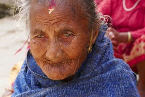 Un intenso ritratto di una donna Newari: all'età di 77 anni, 7 mesi, 7 settimane, 7 giorni e 7 ore gli uomini e le donne di questa etnia vengono onorati come "Divinità anziane" tramite una cerimonia rituale denominata "Janku" e per l'occasione indossano un paio di particolari orecchini di colore oro con una decorazione rossa. Questo rituale viene celebrato più volte durante la vita dei Newari: ad 88 anni, 8 mesi ed 8 giorni, a 99 anni, 9 mesi e 9 giorni, a 105 anni, 8 mesi ed 8 giorni. Si crede che, il raggiungimento di queste età anagrafiche, coincida  con particolari momenti in cui la persona potrebbe incorrere in problemi di salute ma, proprio tramite queste cerimonie si venerano alcune Divinità (come il Sole e la Luna) per allontanare possibili malattie ed augurare lunga vita. Villaggio di Khokanà, Nepal 2018.