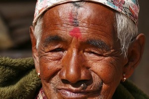 Ritratto di un uomo Newari: all'età di 77 anni, 7 mesi, 7 settimane, 7 giorni e 7 ore gli uomini e le donne di questa etnia vengono onorati come "Divinità anziane" tramite una cerimonia rituale denominata "Janku" e per l'occasione indossano un paio di particolari orecchini di colore oro con una decorazione rossa. Questo rituale viene celebrato più volte durante la vita dei Newari: ad 88 anni, 8 mesi ed 8 giorni, a 99 anni, 9 mesi e 9 giorni, a 105 anni, 8 mesi ed 8 giorni. Si crede che, il raggiungimento di queste età anagrafiche, coincida  con particolari momenti in cui la persona potrebbe incorrere in problemi di salute ma, proprio tramite queste cerimonie si venerano alcune Divinità (come il Sole e la Luna) per allontanare possibili malattie ed augurare lunga vita. Villaggio di Bungamati, Nepal 2018.