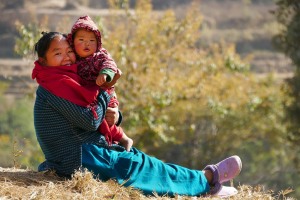 Una giovane mamma Newari tiene in braccio la sua bambina e sorride all'obiettivo della mia macchina fotografica mentre scatto loro questo bel ritratto, dintorni del villaggio di Bungamati, Nepal 2018.