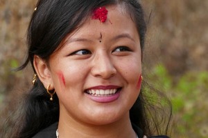 Una devota di etnia Newari è appena uscita dal sacro Tempio dedicato alla Dea tantrica Vajrayogini, una delle rare divinità femminili della mitologia buddhista (Vajrayogini era un'asceta errante che raggiunse un livello di illuminazione equivalente a quello del Buddha): sulla sua fronte è presente in modo evidente il "Tilaka", il segno rosso composto da un impasto di kumkum (la polvere a base di curcuma mischiata con la calce spenta che dona il tipico colore rosso) e pasta di sandalo, mentre al centro degli occhi vi è un segno nero (il "Bindi", parola che deriva dal sanscrito Bindu e significa goccia, punto) mediante l'applicazione di cenere consacrata di qualche rituale sacro. Il Bindi è considerato una sorta di sbocco dell'energia Kundalini che trattiene questa energia all'interno del corpo umano. E' un simbolo con cui celebrare l'intelletto umano, in tal modo si assicura la purezza dei propri pensieri, azioni e abitudini, la propria capacità di agire con coraggio e lottare per la verità. Villaggio di Pharping, Nepal 2018.
