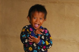 Chandra, questo il nome della bambina Tharu ritratta, viene immortalata mentre giochiamo a fare una gara di linguacce: lei me ne fa una sonora e con il doppio movimento di mani e braccia, villaggio di Harnari, Chitwan National Park, Nepal 2018.