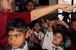 Nell'aula gremita di bambini festanti della Shree Bal Bikosh Basic School, una turista distribuisce caramelle, Kathmandu, Nepal 2018