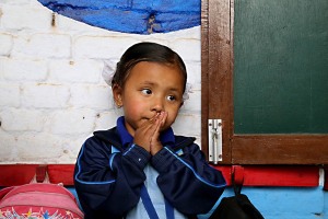 Una bimba nepalese dallo splendido nome di "Savitri" (che significa Sole) attende seduta sulla panca della scuola che arrivi a prenderla la sua mamma, Shree Bal Bikosh Basic School di Cheetrapati, nella capitale Kathmandu, Nepal 2018