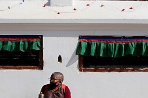 Ai piedi dello Stupa di Bodhnath un monaco nepalese chiede le offerte ai fedeli imbracciando la ruota di preghiera (denominata Pray Wheel) che, con il movimento del polso, fa girare attraverso l'impugnatura di legno (il cosiddetto "albero della vita") e mediante un perno di piombo con una catenella attaccata al cilindro per facilitarne la rotazione: si crede che tale movimento permetta di diffondere le preghiere in modo più efficace, così come le bandierine tibetane diffondono le preghiere nell'aria anche le ruote di preghiera hanno un effetto simile. Sull'esterno vengono inserite a rilievo alcune preghiere (in particolare il mantra "Om Mani Padme Hum" in sanscrito) che sono contenute anche all'interno della ruota mediante lunghe pergamene di riso scritte a mano arrotolate nella cavità del cilindro stesso. Valle di Kathmandu, Nepal 2018