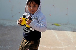 Un bambino nepalese, appartenente alla classe dei Brahmini di etnia Brahman, gioca con il suo binocolo nel piazzale del Tempio di Bodhnath, Kathmandu, Nepal 2018