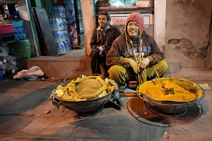 L'incrocio di Asan Tole, dove si intersecano sei strade, è disseminato di venditori di verdure e spezie: ogni giorno da qualsiasi villaggio della Valle di Kathmandu giungono sin qui i prodotti ortofrutticoli più disparati. Qui è ritratto un venditore di polvere di curcuma. Il Tempio di Annapurna, nel lato sud orientale della piazza, è giustamente dedicata alla Dea dell'abbondanza, raffigurata con una ciotola d'argento ("purana") colma di cereali. Nepal 2018