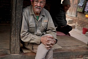 Nel cortile Mul Chowk, adiacente alla Porta di Bhairab e vicino al Palazzo Reale di Patan, un anziano nepalese appartenente alla casta dei "Kshatriya" (dell'etnia Chhetri) si gode il fresco del tardo pomeriggio, Nepal 2018
