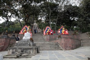 Ai piedi della collina, lungo la scalinata in pietra che si inerpica lungo il fianco orientale e porta alla sua sommità, dove si trova il Tempio buddhista di Swayambhunath (patrimonio dell'Umanità Unesco), si incrociano queste tre statue raffiguranti il Buddha dipinte con colori molto vivaci: Swayambhunath prende il nome anche di "Tempio delle scimmie", in quanto è invaso dai macachi che sono, di fatto, i proprietari assoluti del territorio circostante. Viziati dai pellegrini con continue offerte di cibo e di frutta, non possono certamente lamentarsi per il trattamento a loro riservato. Kathmandu,  Nepal 2018.