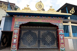All'ingresso del Monastero Sakya Tharing si possono contemplare, tra l'altro, queste notevoli sculture in metallo ricoperte di lamina d'oro riproducenti due gazzelle (simbolo di pacificità e di quiescenza yogica) e la Ruota del Dharma (in sanscrito "Cakra") che si compone di un mozzo centrale e di 8 o più raggi e di un cerchione esterno. Nella cultura Buddhista la ruota è strettamente associata al concetto della Ruota del Dharma messa in moto da Buddha durante la prima esposizione pubblica della sua dottrina a Sarnath presso Benares (l'attuale Varanasi) nel Parco delle Gazzelle. Secondo i tre addestramenti della pratica buddhista, il mozzo rappresenta l'addestramento alla disciplina morale che rende stabile la mente; i raggi rappresentano la comprensione della vacuità di tutti i fenomeni, che permette di eliminare alla radice la nostra ignoranza; il cerchione esterno, infine, identifica la concentrazione che permette di tenere salda la pratica della dottrina buddhista. In particolare la Ruota del Dharma simboleggia l'insegnamento buddhista nella sua globalità e ci ricorda che il Dharma abbraccia tutte le cose, non ha nè inizio nè fine, è in movimento e nello stesso tempo immobile. Il nome "Sakya" (dal sanscrito Sa skya che significa "terra pallida"), contraddistingure una delle quattro principali scuole del Buddhismo tibetano (le altre sono il Nyingma, il Kagyu ed il Gelug), insieme al Nyingma ed al Kagyu è una delle sette scuole dei "Berretti Rossi" (dal colore dei berretti indossati dai monaci. Boudhnath, Kathmandu, Nepal 2018.