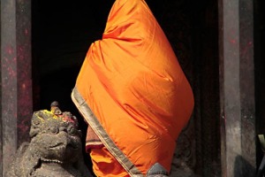 L'ingresso del Krishna Mandir di Patan, il tempio di pietra più antico del Nepal (capolavoro architettonico realizzato nel 1637 dal re Siddhinarsingh Malla totalmente in pietra intagliata): il contrasto di colore tra l'abbigliamento indossato dalla devota ed il grigio chiaro della pietra, crea un effetto particolarmente suggestivo, Nepal 2018