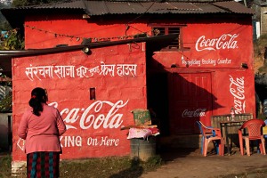 Lungo la strada che porta al villaggio di Chapagaon si incrocia questo chioschetto dove la pubblicità della famosa bevanda americana è dipinta direttamente sulle pareti esterne, Nepal 2018