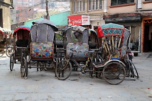 Nel quartiere Chhetrapati di Kathmandu, tra centinaia di fili elettrici aggrovigliati e tesi tra un palo e l'altro, la piazzetta è "invasa" dai ciclorisciò parcheggiati in attesa dei clienti, Nepal 2018