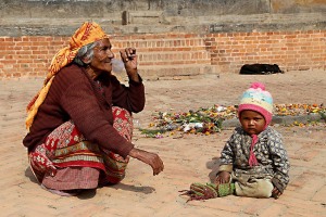 Accanto al Palazzo Reale di Patan, nel piazzale antistante, una piccola bambina nepalese appartenente agli "Harijan" (gli intoccabili) chiede l'elemosina insieme alla nonna, Nepal 2018