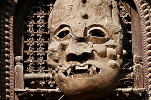 Su un'antica finestra in legno intagliato di Kathmandu troneggia questa maschera in legno anch'essa intagliata a mano, posta come potente feticcio contro la cattiva sorte, Nepal 2018.