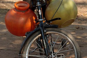 Nel villaggio di Belur, come in molti villaggi in India, non vi è acqua corrente nelle abitazioni e, pertanto, occorre percorrere anche chilometri per raccoglierla nei rari pozzi esistenti: una bicicletta può allievare la fatica di raccogluerla e trasportarla a destinazione. Regione del Karnataka, India 2015.