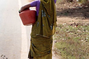 Una donna torna verso la sua casa dopo aver raccolto l'acqua in un pozzo a qualche chilometro di distanza dal villaggio di Belur.Regione del Karnataka, India 2015.
